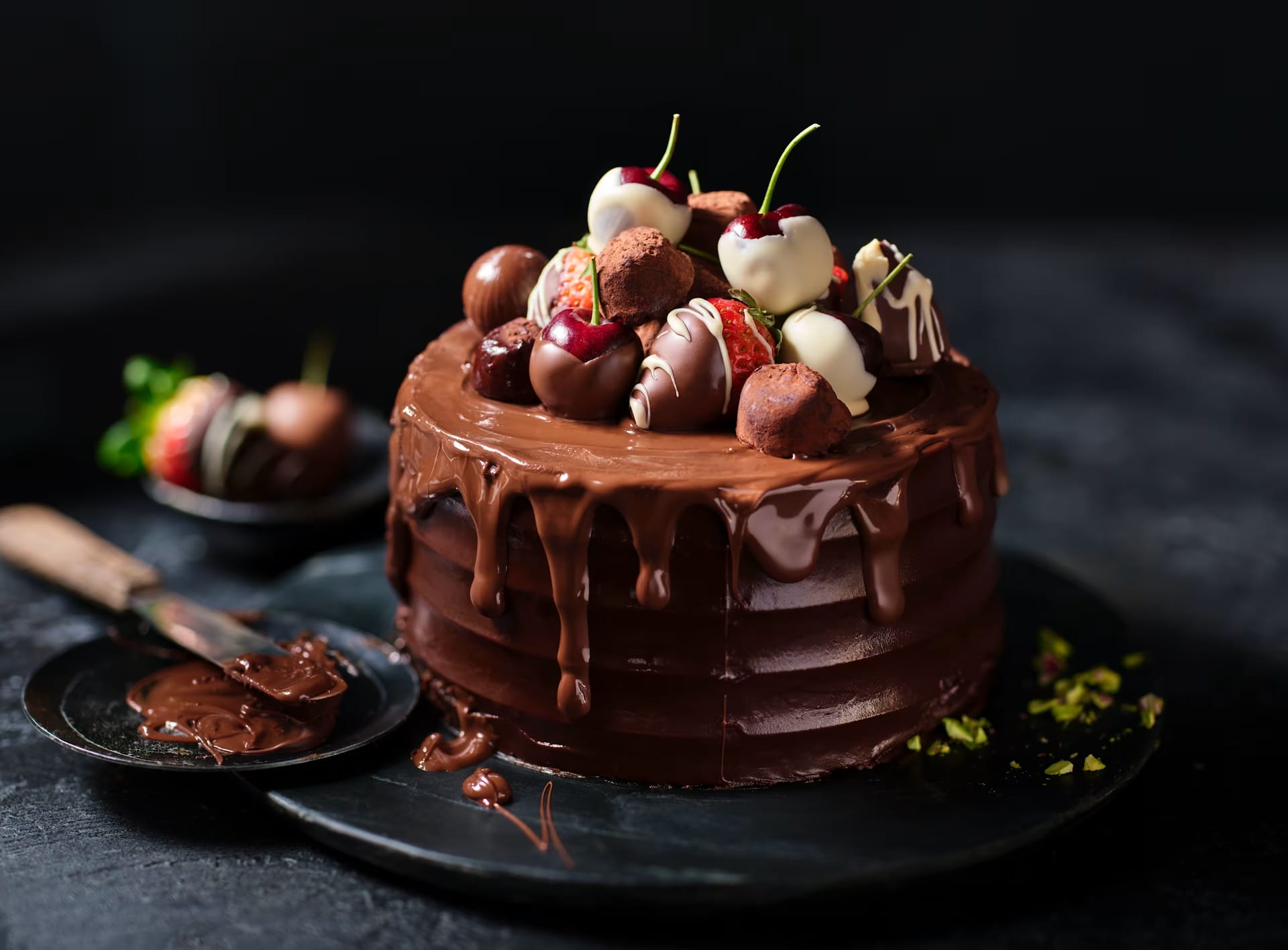 Chocolate drip cake topped with truffles and dipped cherries